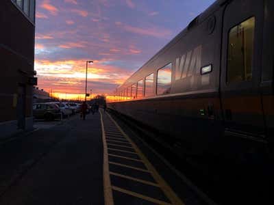 VIA Rail train at the Cobourg station under a dramatic sunset sky