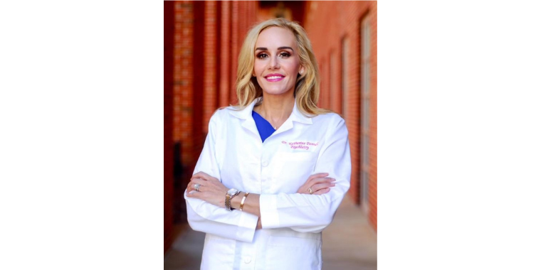 Katherine Pannel stands in front of red brick with arms crossed in her white coat. 