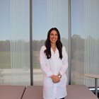 Dr. Kennedy stands in front of shaded window in her white coat. 