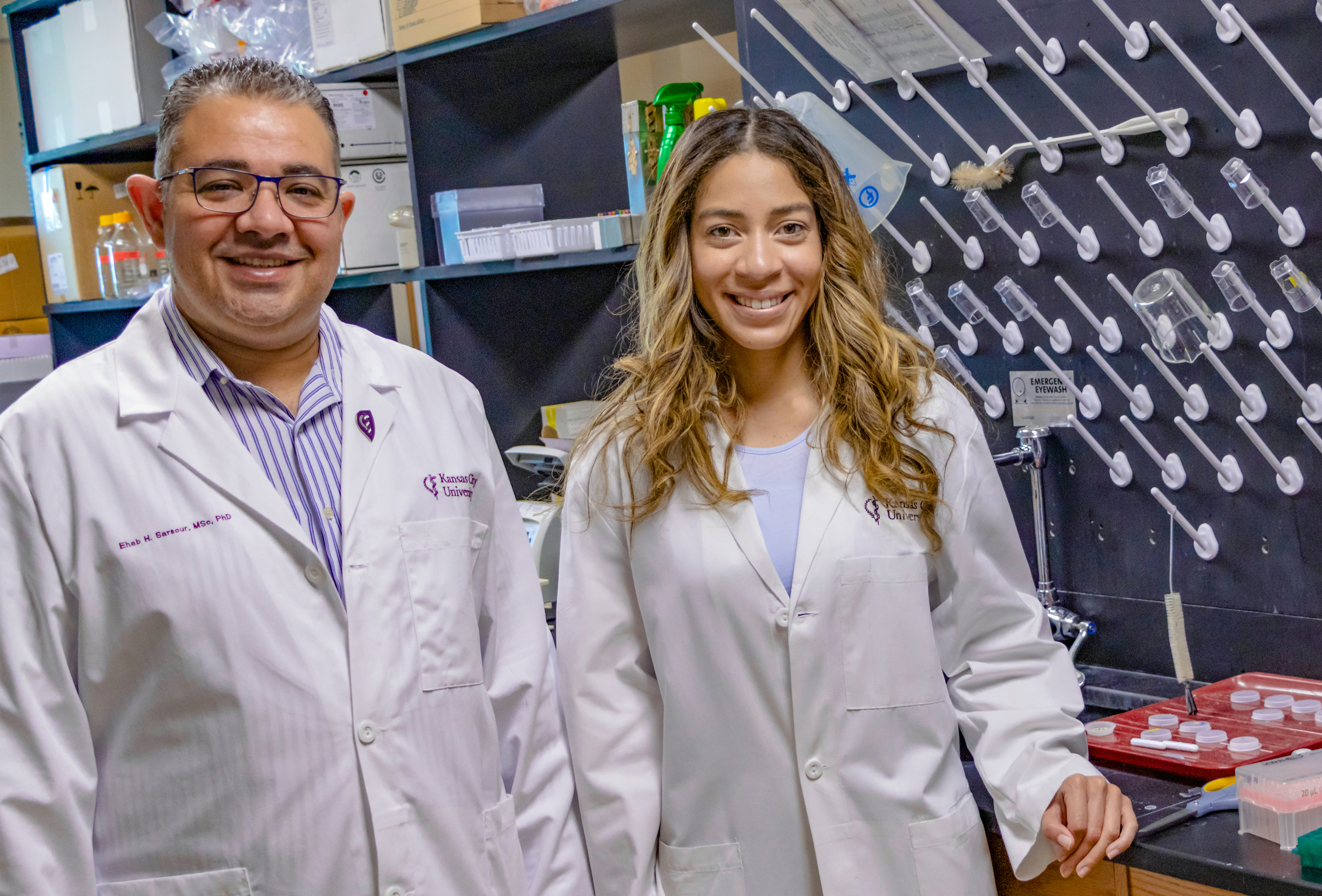  KCU researcher Ehab Sarsour, PhD, and fourth-year medical student Katiana Hebbert in white coats in a lab. 