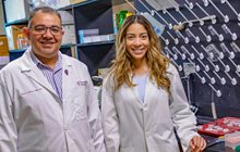  KCU researcher Ehab Sarsour, PhD, and fourth-year medical student Katiana Hebbert in white coats in a lab. 