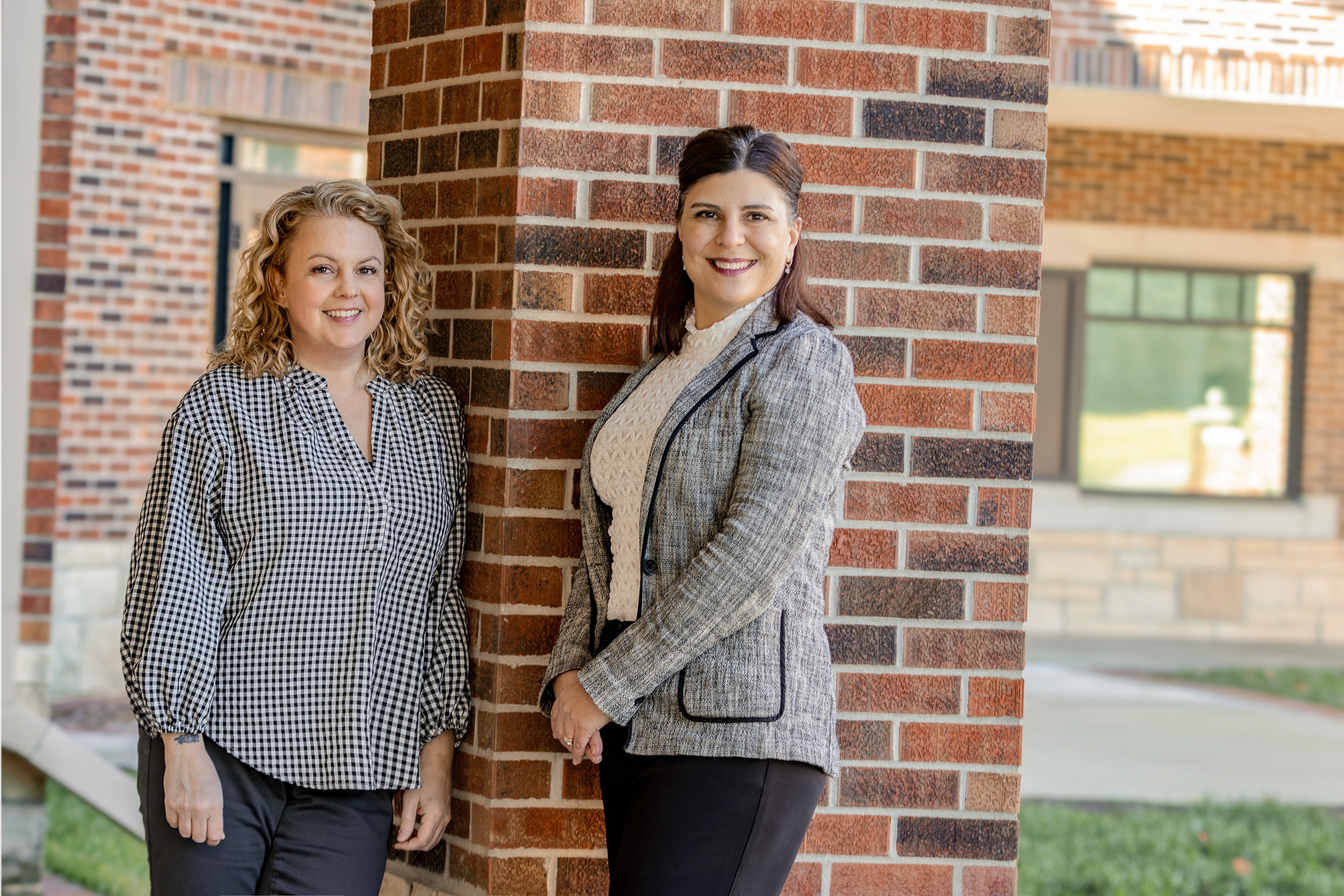 Drs. Jennifer Fugate and Nicki Zieber smile together in front of brick wall. 