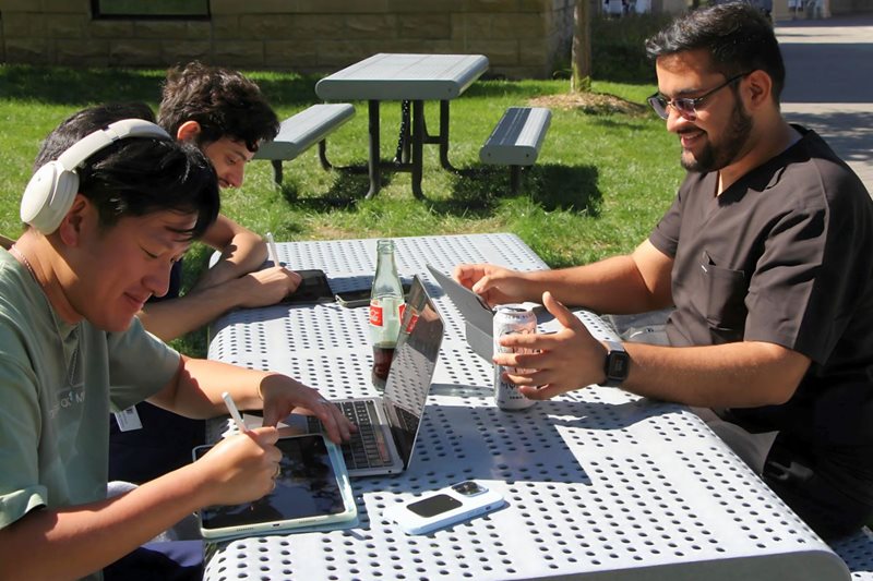 Students using iPads outside at a picnic table