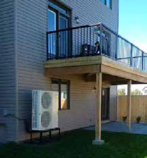 Outdoor air-source heat pump installed beside a residential building, supporting strategic electrification and lower-carbon heating and cooling.