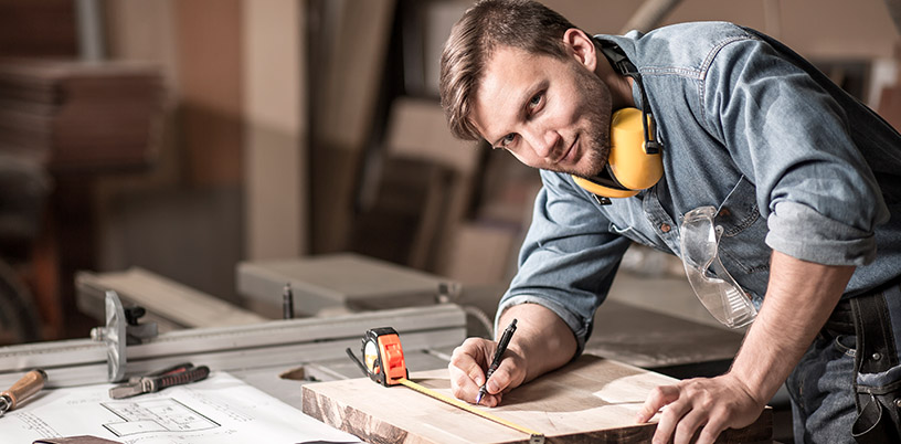 a trades carpenter measuring out pieces of wood to cut