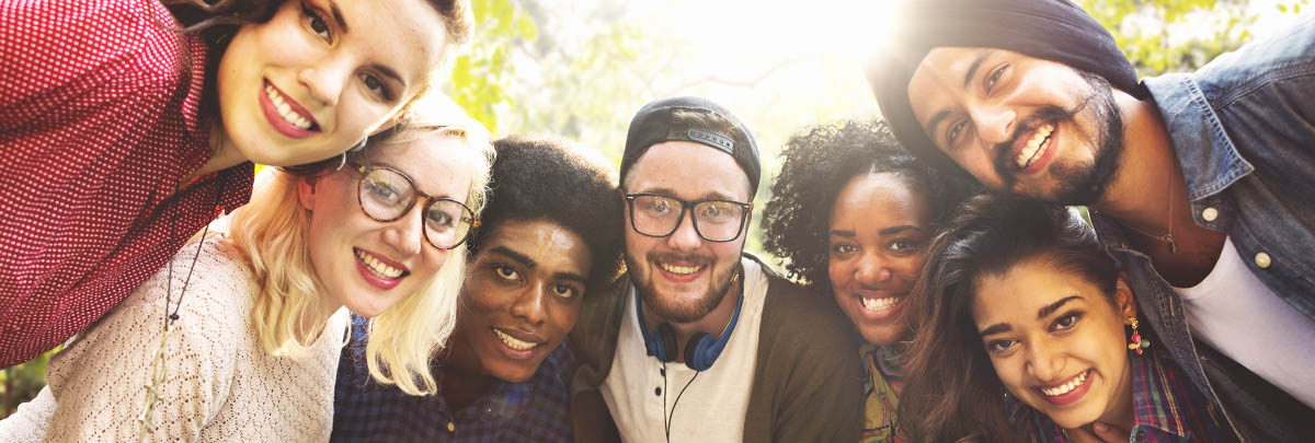 a diverse group of Canadian students huddled around a camera and smiling