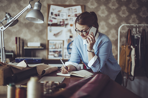 a woman in her office, picking up a phone while running her fashion business