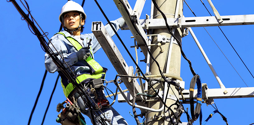 a power line technician who is fixing lines high up on a hydro pole