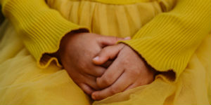 little girl with hands folded in lap