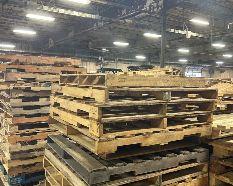 Recycled wooden pallets stacked inside the PRO Pallet facility