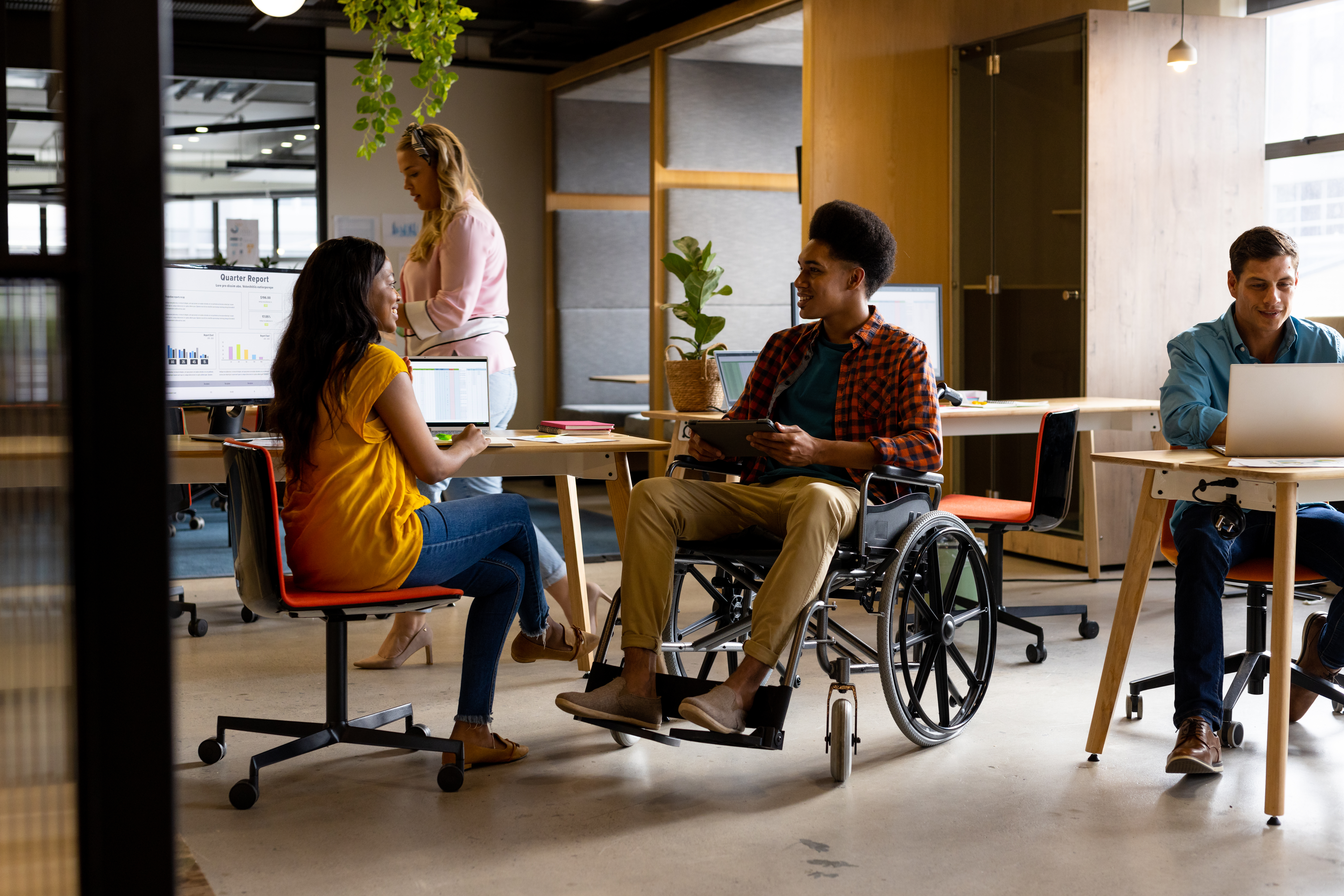 Woman sitting at desk next to man in wheelchair working in office space