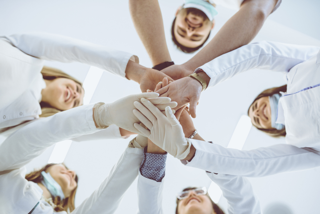 Five dentists smiling and high-fiving.