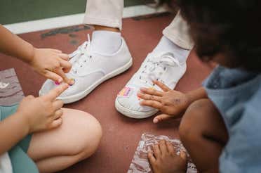 Kids placing vinyl on shoes.