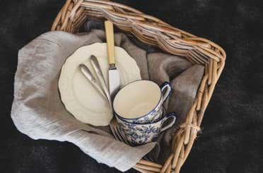 Plates, cups, and cutlery in a basket.