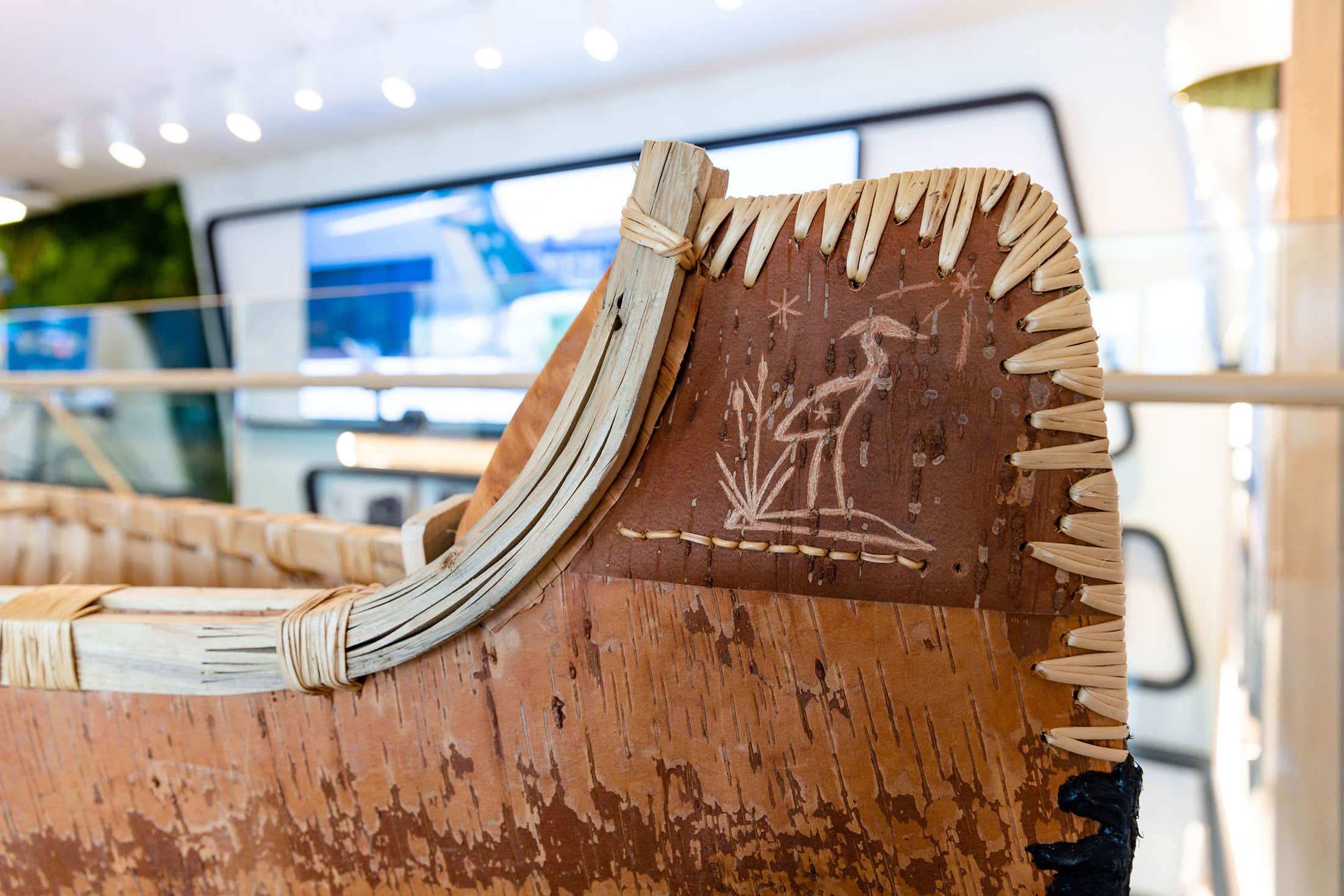 A wooden canoe featuring intricate carved designs along its sides, showcasing craftsmanship and artistry.