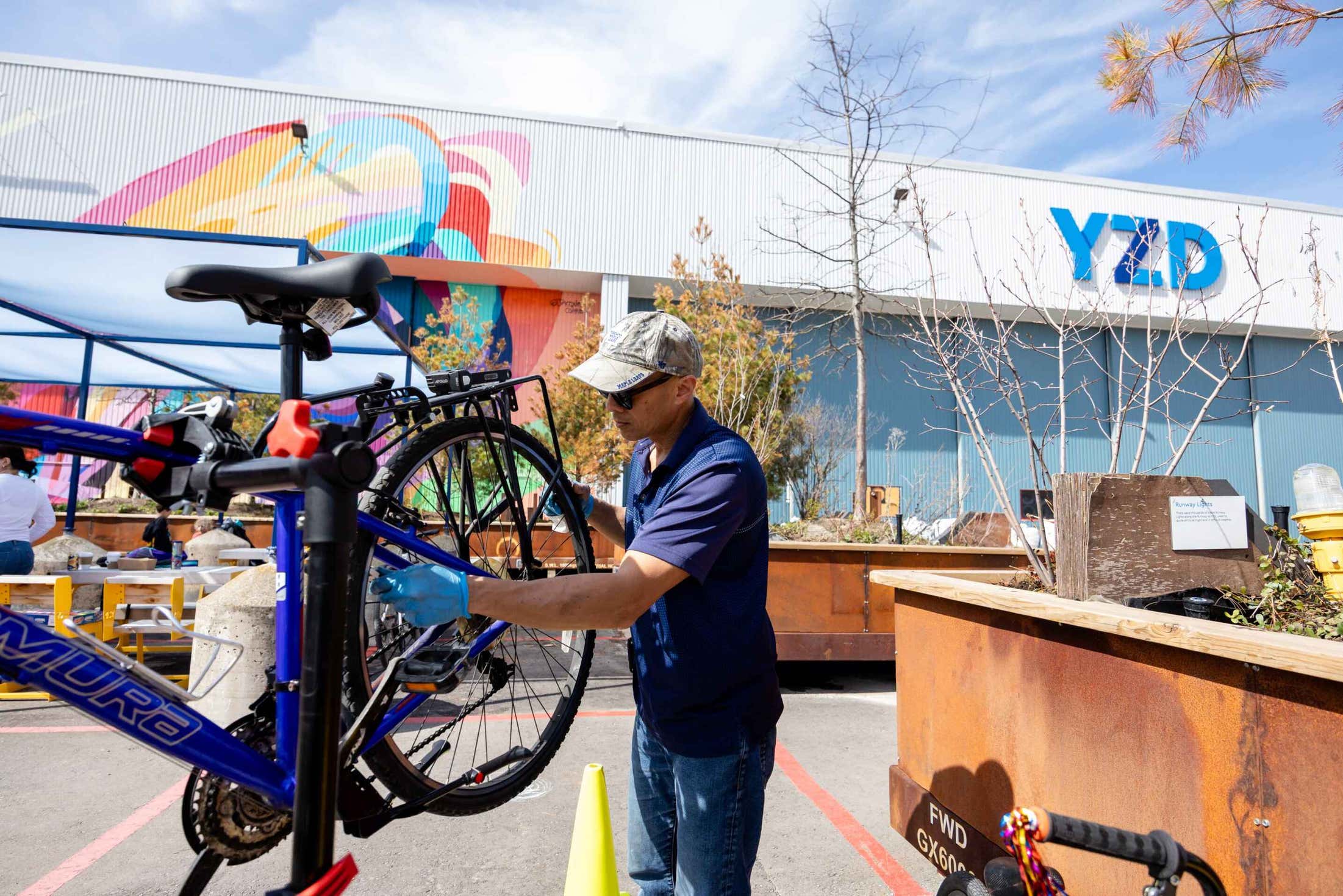 A man stands outdoors, holding a bicycle with a focused expression on his face.