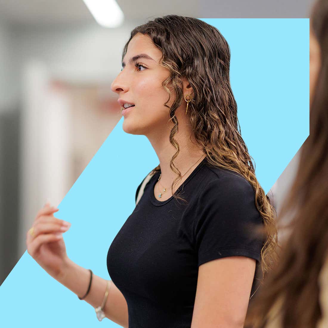 A woman with long hair engaged in conversation with another person, both appearing attentive and focused.