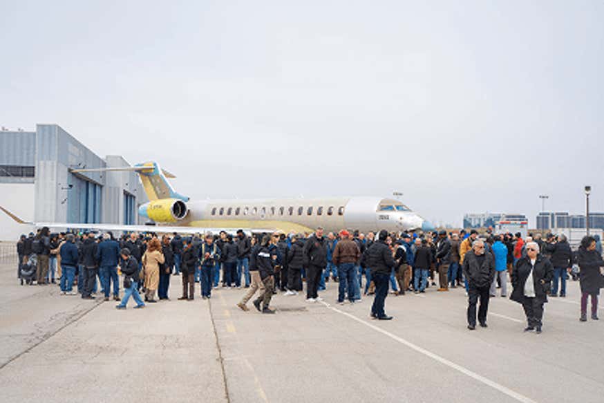 Photo of people outdoors surrounding an airplane